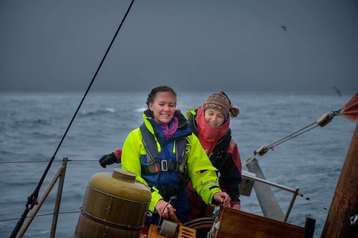 A passenger takes the helm under the watchful eye of The Swan Mate Maggie Adamson